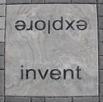 Paving stone engraved with words: invent, explore.