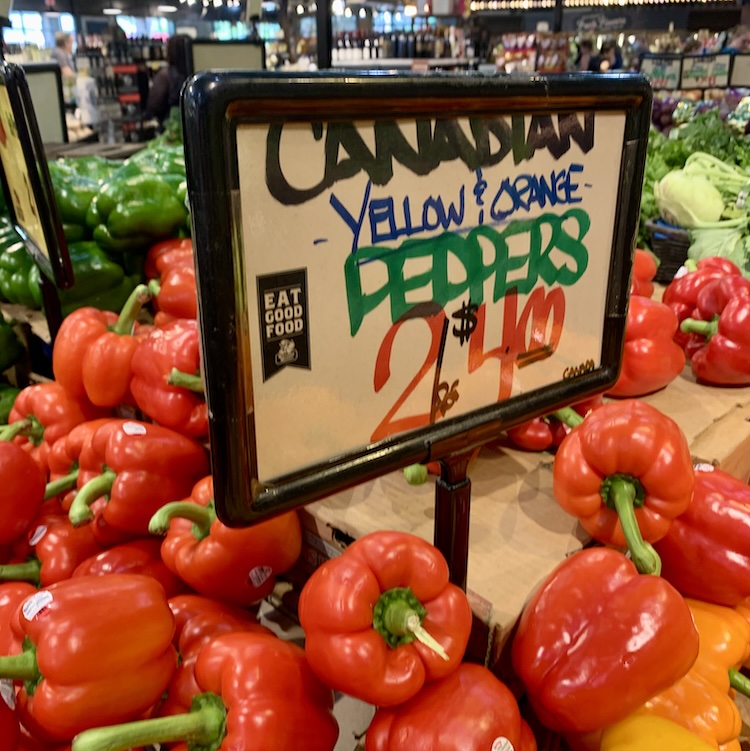 Canadian peppers at Westborn Market. Sign shows yellow & orange peppers 2 for $4, but mostly red peppers visible.